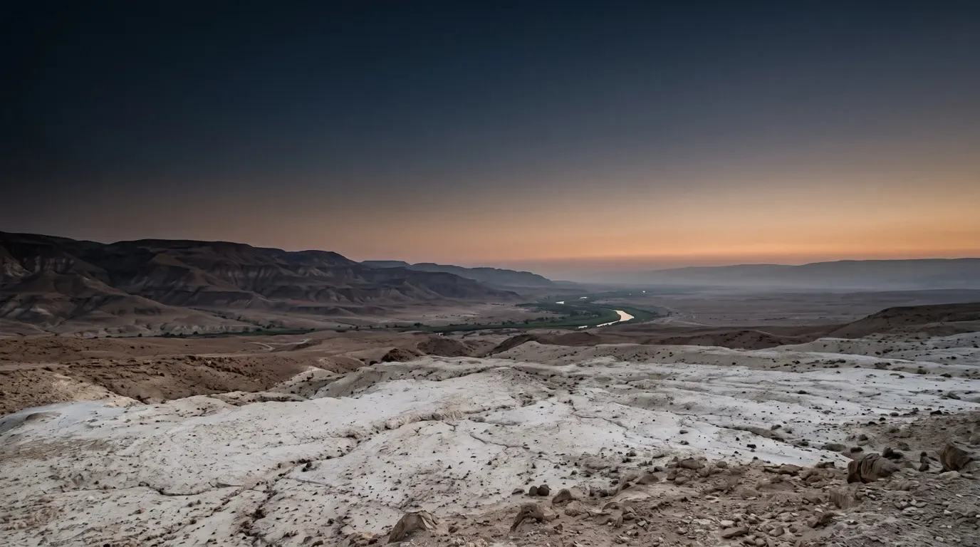 The green thread of the Jordan winding through white marl badlands, the far hills rising in layers.