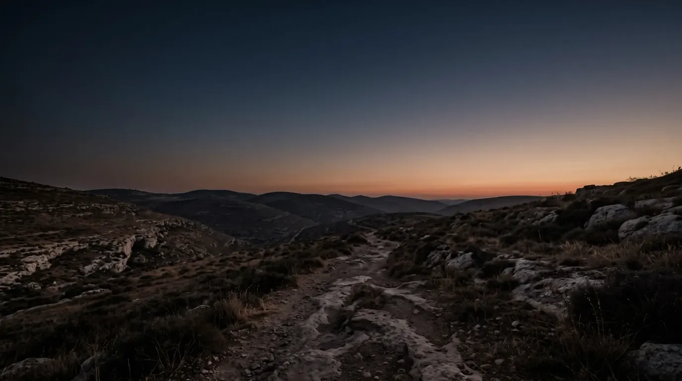 The last red of sundown over folded hills going into shadow.