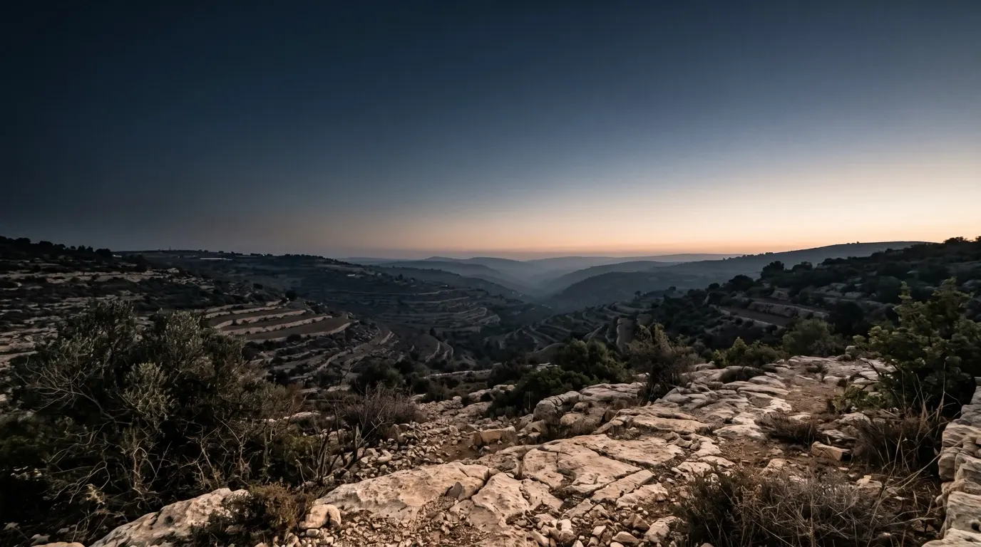A wide dark valley, the first light breaking along its far rim.