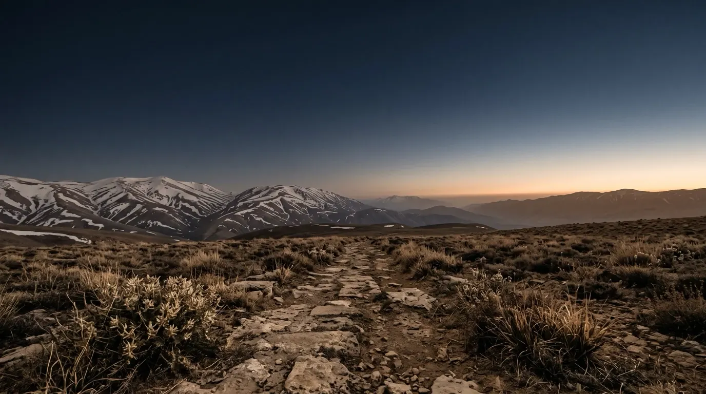 A high plateau under snow-streaked ridges, an old stone track running across it.
