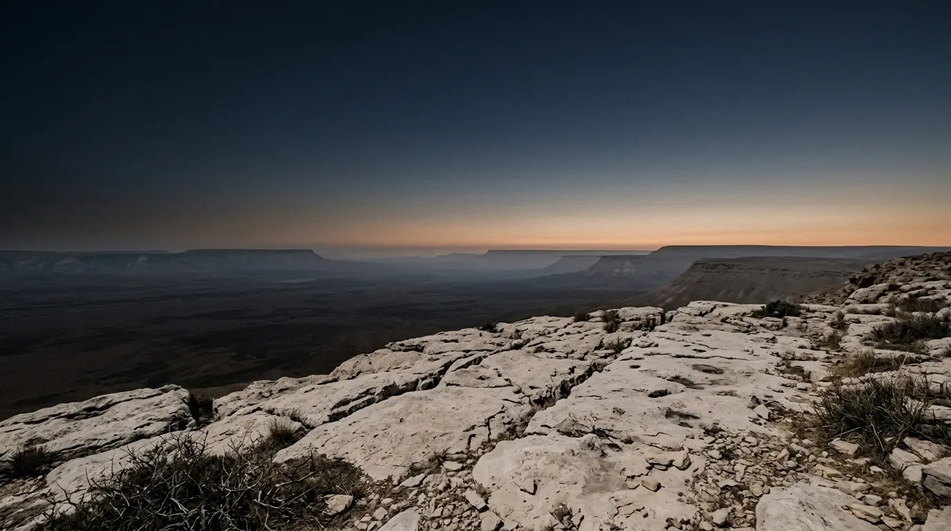 A high open shoulder of bare pale rock at night, the whole dark plain lying far below.