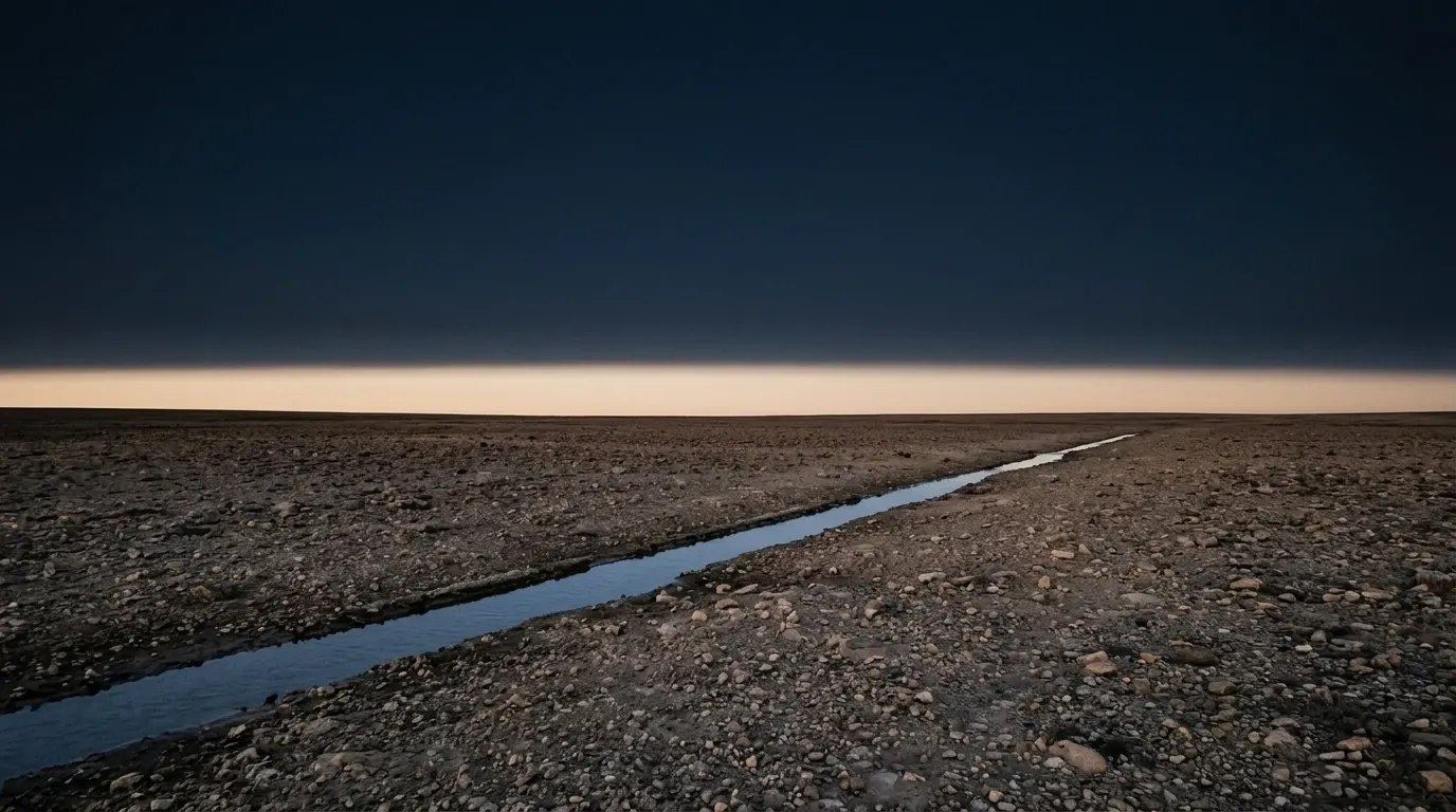 Dry stony ground with a thin channel of clear running water cutting straight across it.
