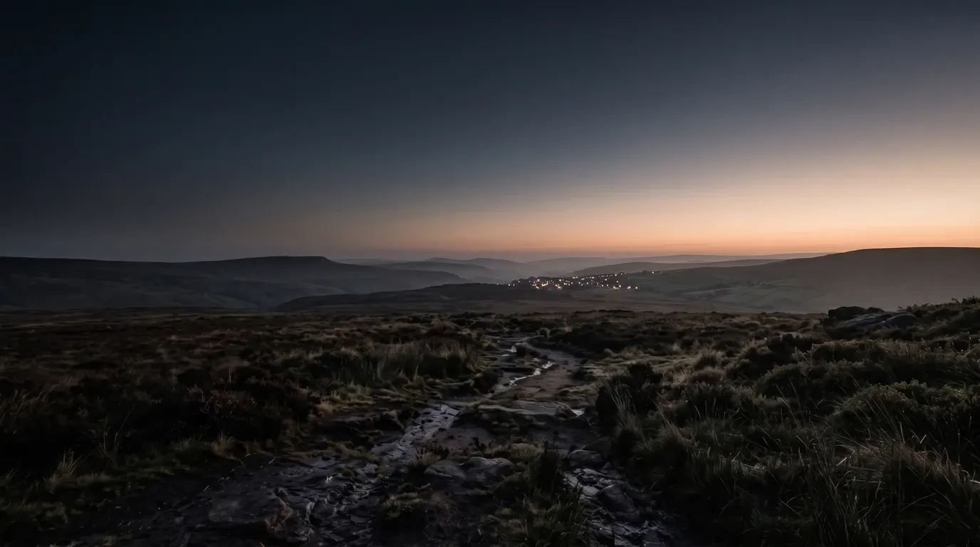 A hill town’s windows lit at dusk, small and unmistakable across miles of open country.