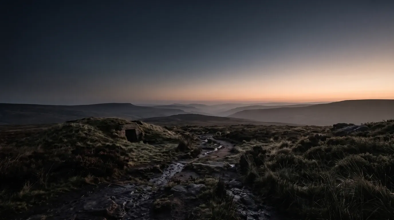 First morning light reaching a low rock-cut opening in a grassy hillside.