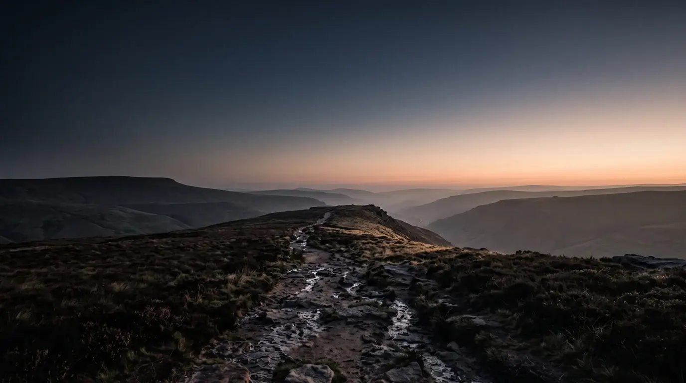 A stony path climbing over a bare ridge, the country beyond opening out in haze.