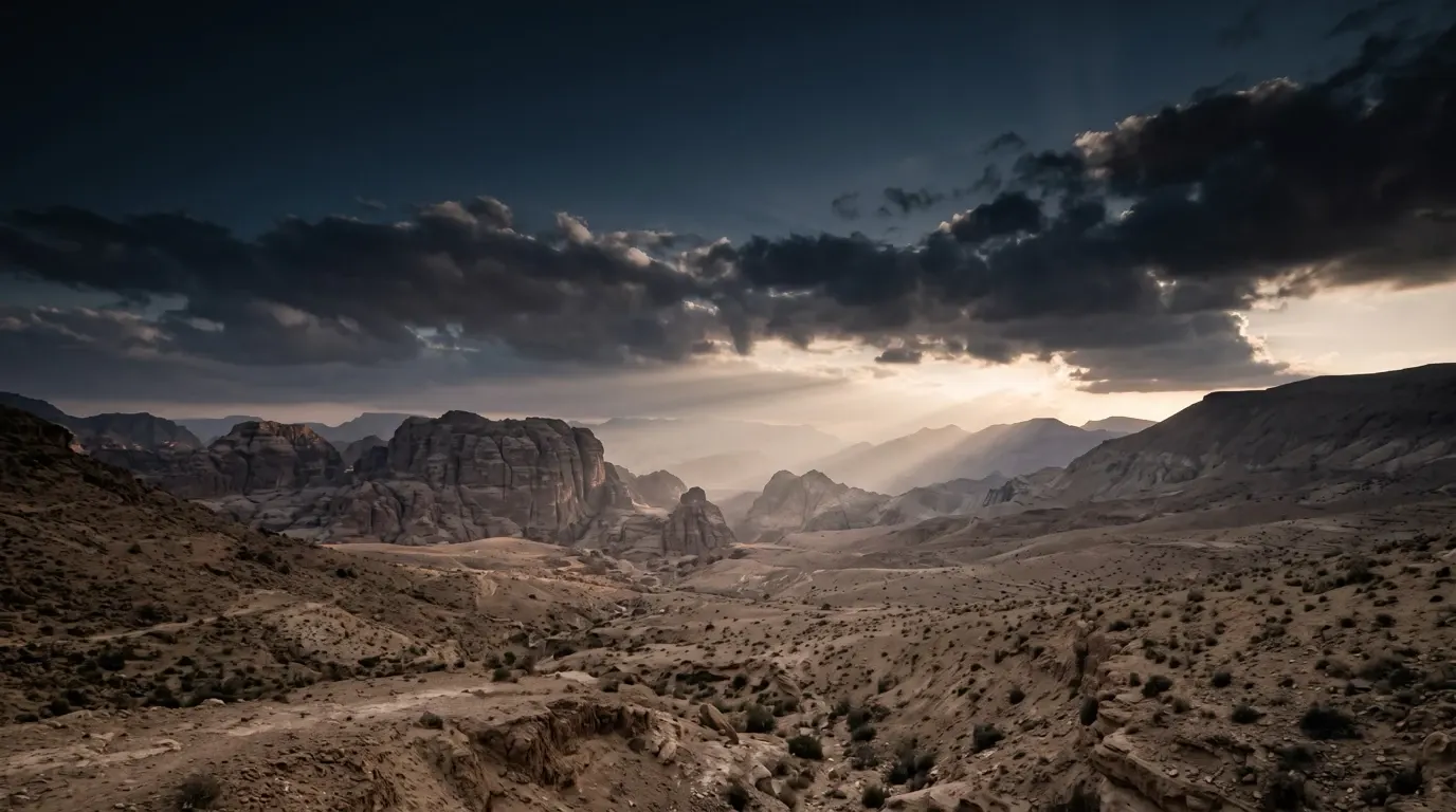 Light breaking through the clouds in broad beams across a wide valley.