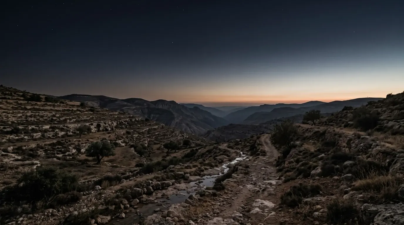 The first light rising along the horizon over a wide dark valley.