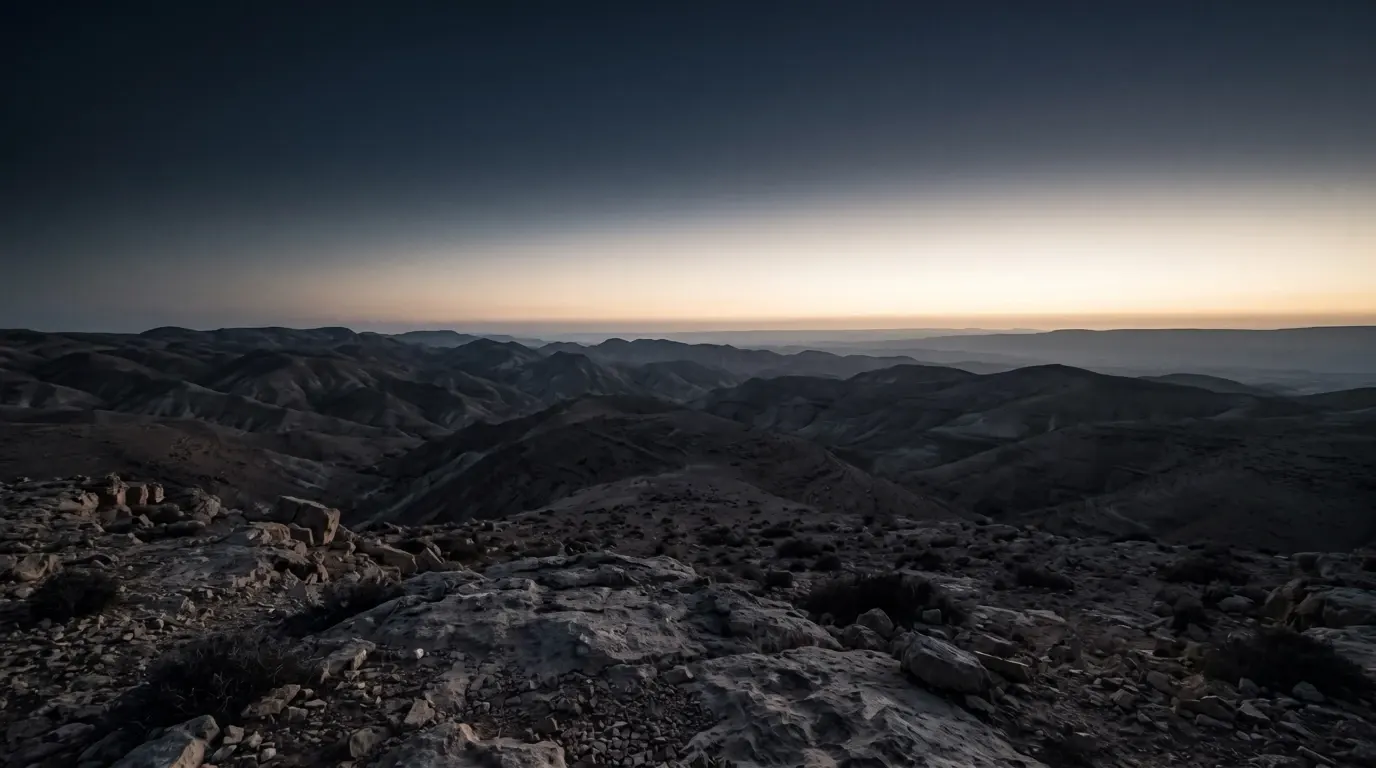 Range after range of dark hills seen from a summit, the eastern sky beginning to pale.