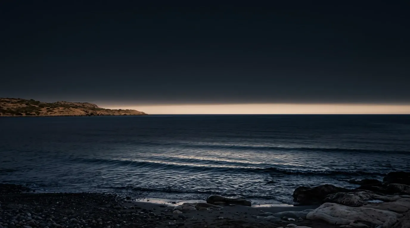 The far edge of the sea at first light, a rocky headland on the left.