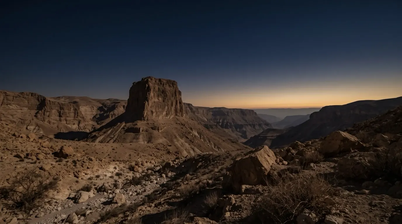 A great sheer crag of rock standing above a desert valley.