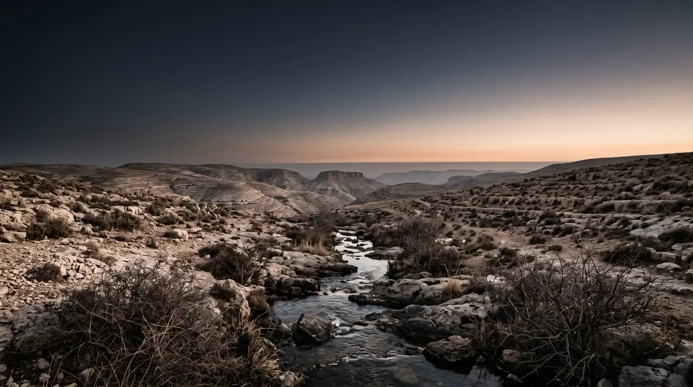 A small brook of clear water running between rocks through dry hills.