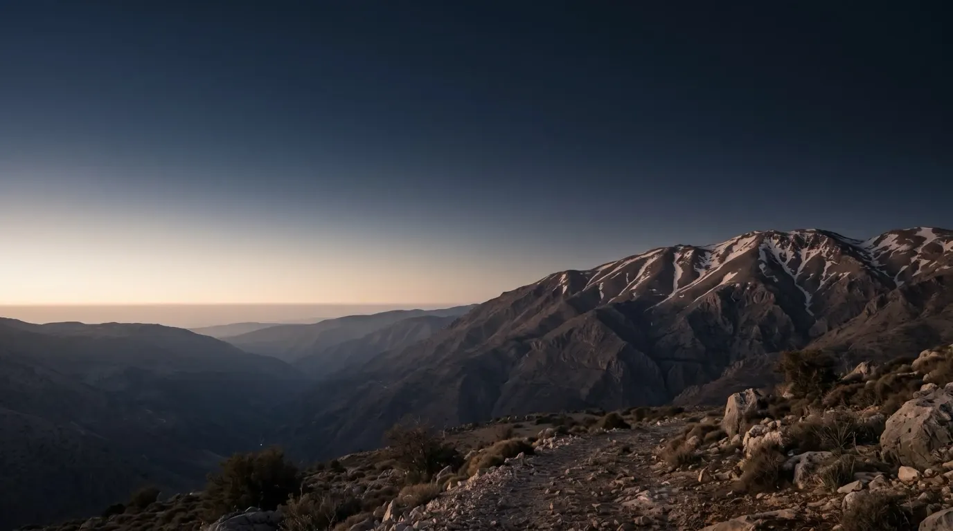 The snow-streaked summit of a great high mountain seen across a deep valley.