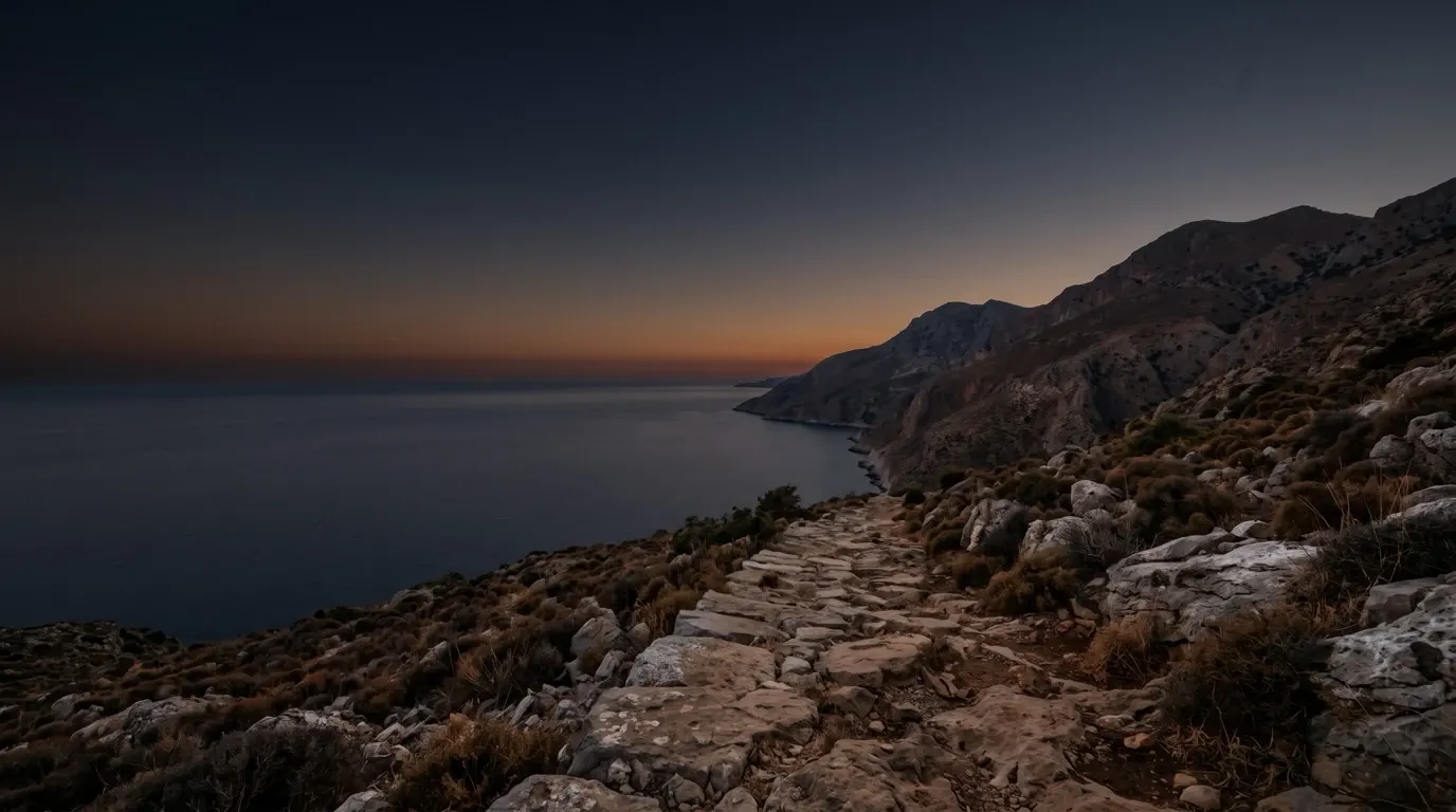 Steep mountains above a rocky coast, the sea calm below.