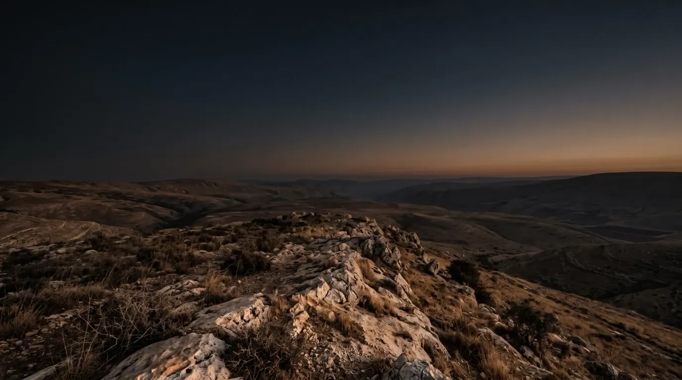 A bare, dry ridge of pale rock above a wide valley, its grass without dew or rain.